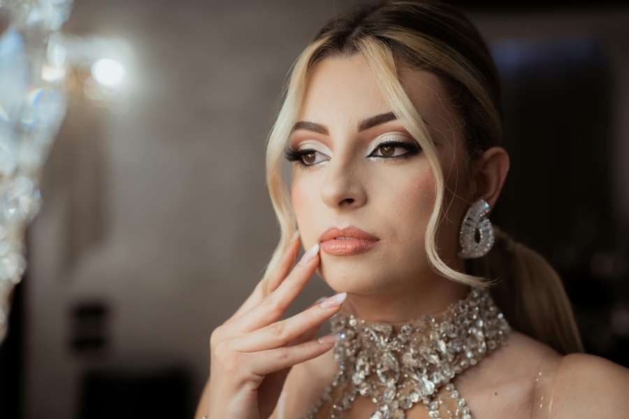 Gros plan sur le visage d'une femme élégante portant un maquillage de soirée sophistiqué et des bijoux étincelants.