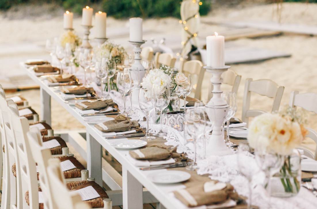 Table de réception en plein air ornée de bougies blanches et fleurs claires illustrant des idées décoration mariage minimaliste et épurée.