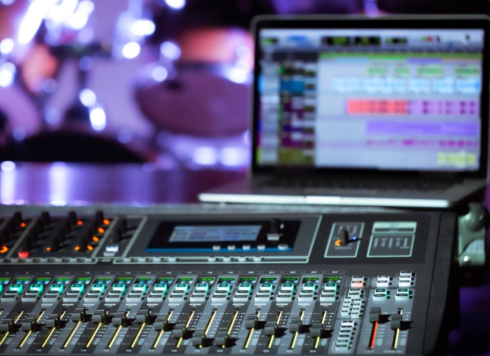 Table de mixage audio numérique et ordinateur portable allumé illustrant les critères pour choisir le bon DJ de mariage.